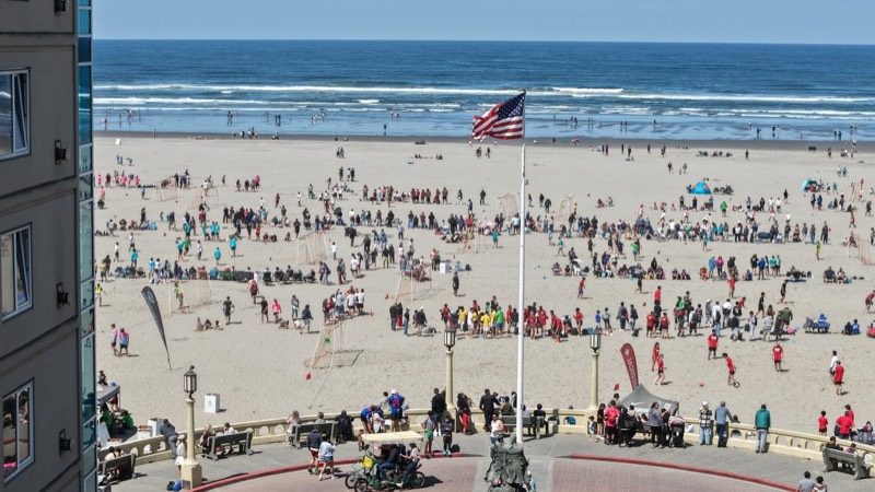 Soccer In The Sand games underway on the beach beneath an American flag