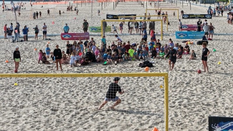 A Soccer In The Sand goalkeeper defends the net during a beach soccer clinic